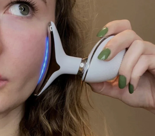 woman using a portable face massager with blue light on her face